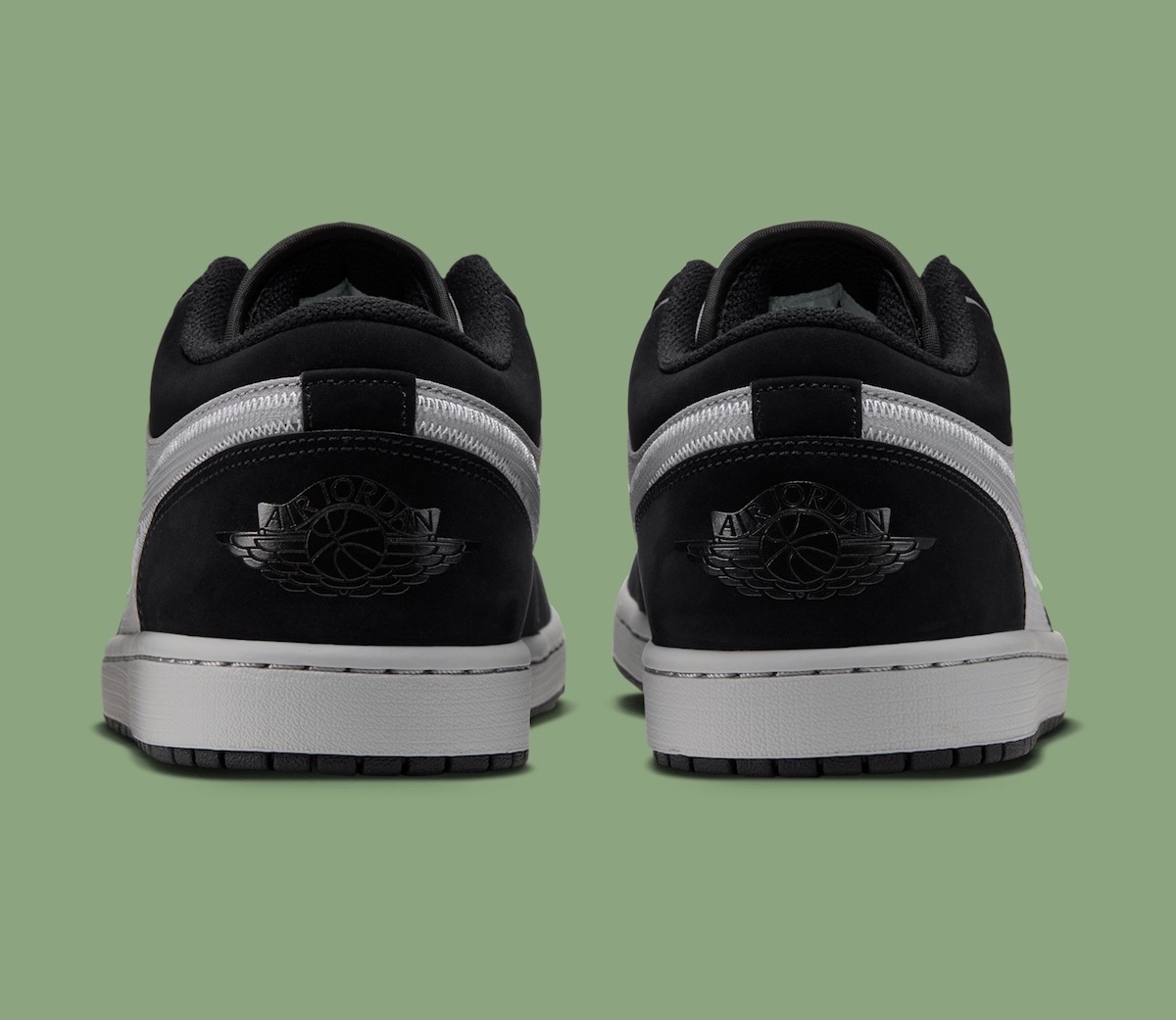 Talones del Air Jordan 1 Low Light Smoke Grey Barely Volt sobre fondo verde, con el logo Wings negro sobre la gamuza negra, la mediasuela gris y la suela negra
