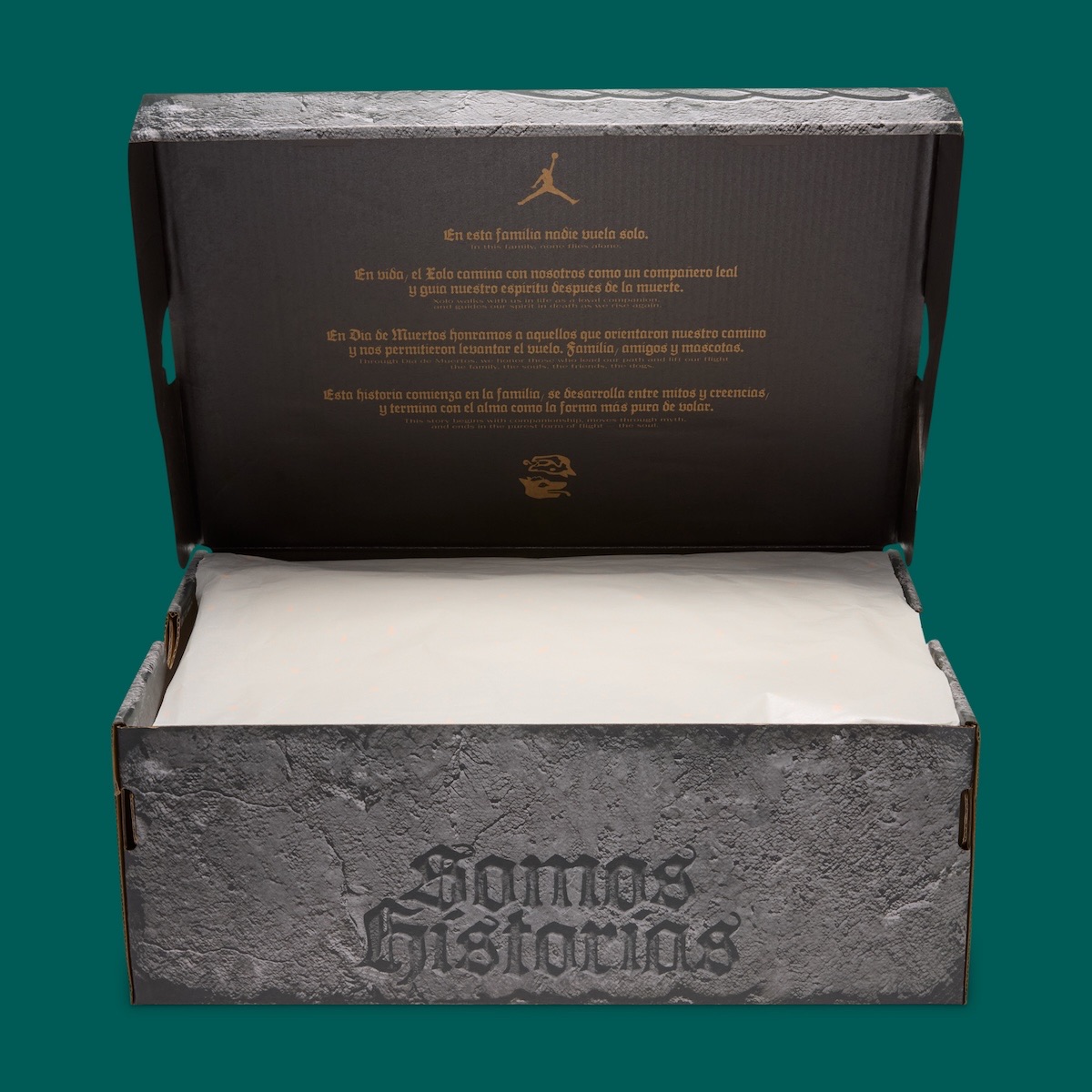 Caja del Air Jordan 1 Low OG Somos Historias abierta sobre fondo verde petróleo, con estampado de piedra gris, las letras góticas Somos Historias al frente y la tapa interior negra con un texto dorado sobre el Xolo y el Día de Muertos