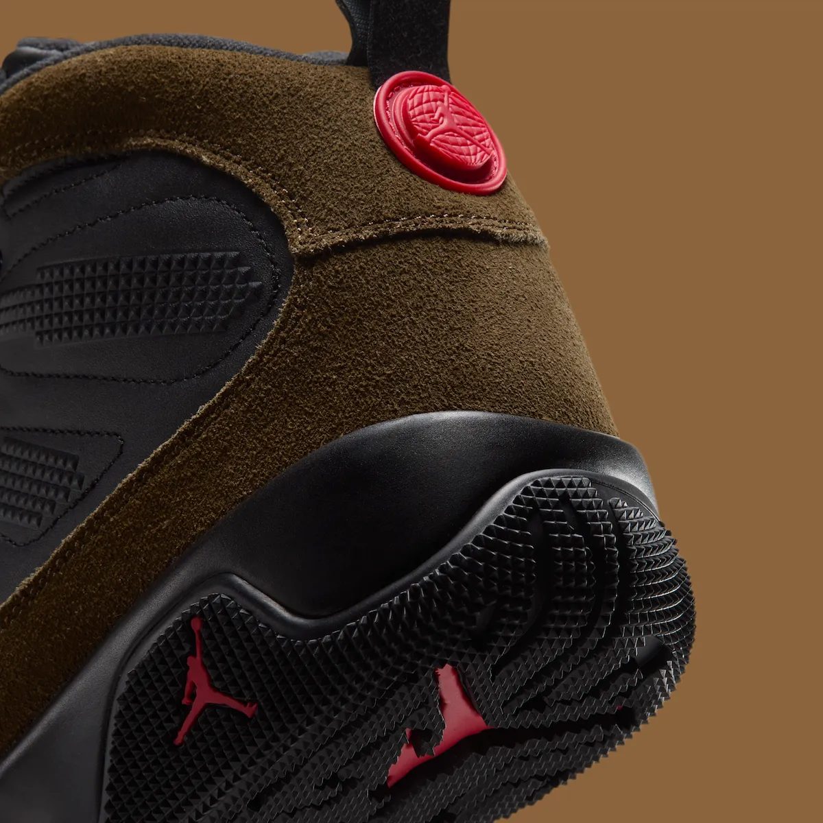 Detalle del talón del Air Jordan 9 Boot Olive sobre fondo marrón, con la gamuza verde oliva, el medallón rojo y el Jumpman rojo en la suela negra