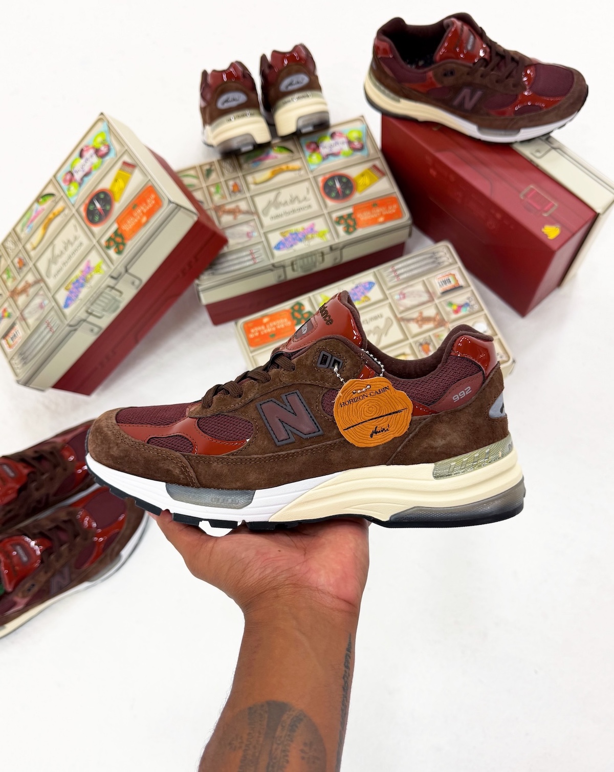 Aminé x New Balance 992 con el hangtag Horizon Cabin junto a las cajas inspiradas en una caja de pesca