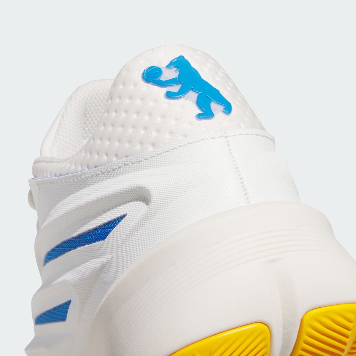 Primer plano del talón de la adidas Crazy Energy Wagner Brothers, con un oso azul sosteniendo una pelota de básquet sobre el material blanco perforado y la suela amarilla asomando abajo