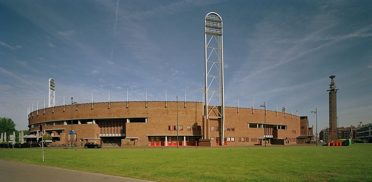 Foto de archivo: el Estadio Olímpico de Ámsterdam, de ladrillo, con su torre de luz y el campo de césped adelante, bajo un cielo azul con nubes