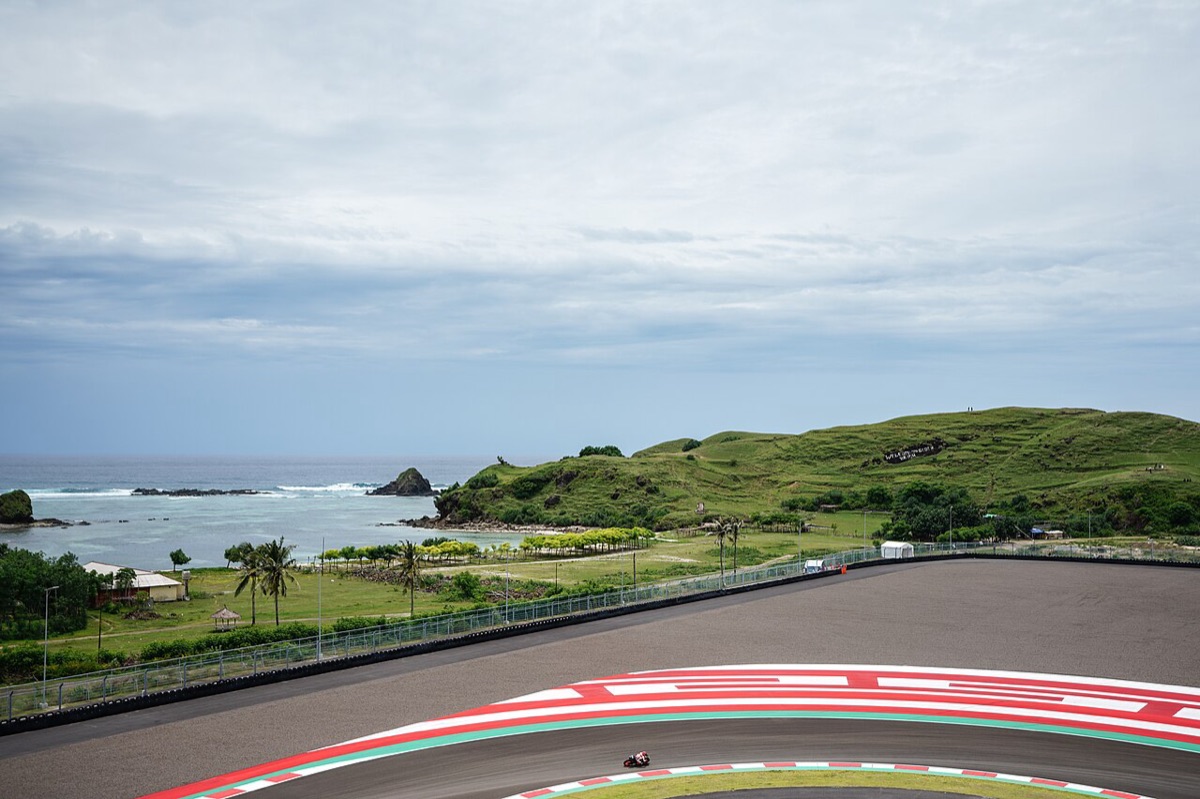 Foto de archivo: una moto de MotoGP pasa por la curva 10 del circuito de Mandalika, con el mar y una colina verde de fondo