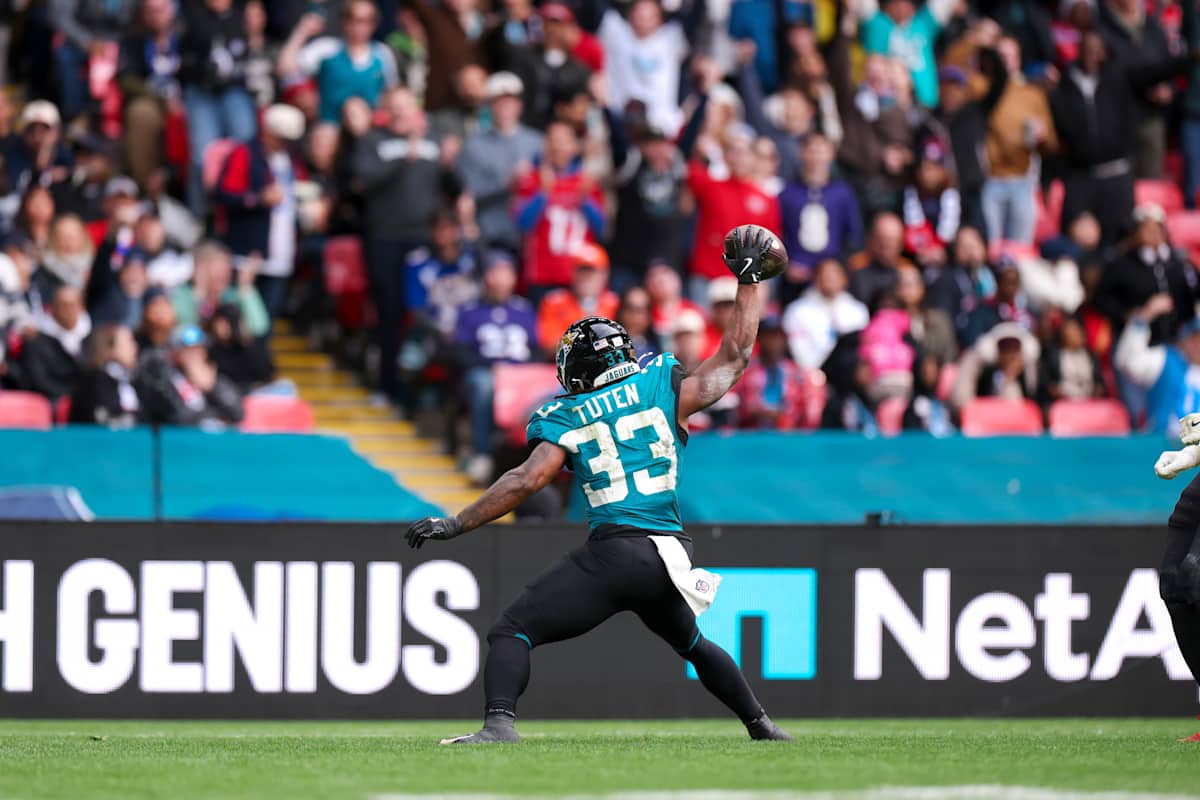 Bhayshul Tuten, con la camiseta turquesa número 33 de los Jaguars, levanta la pelota con la mano derecha delante de la tribuna en Wembley
