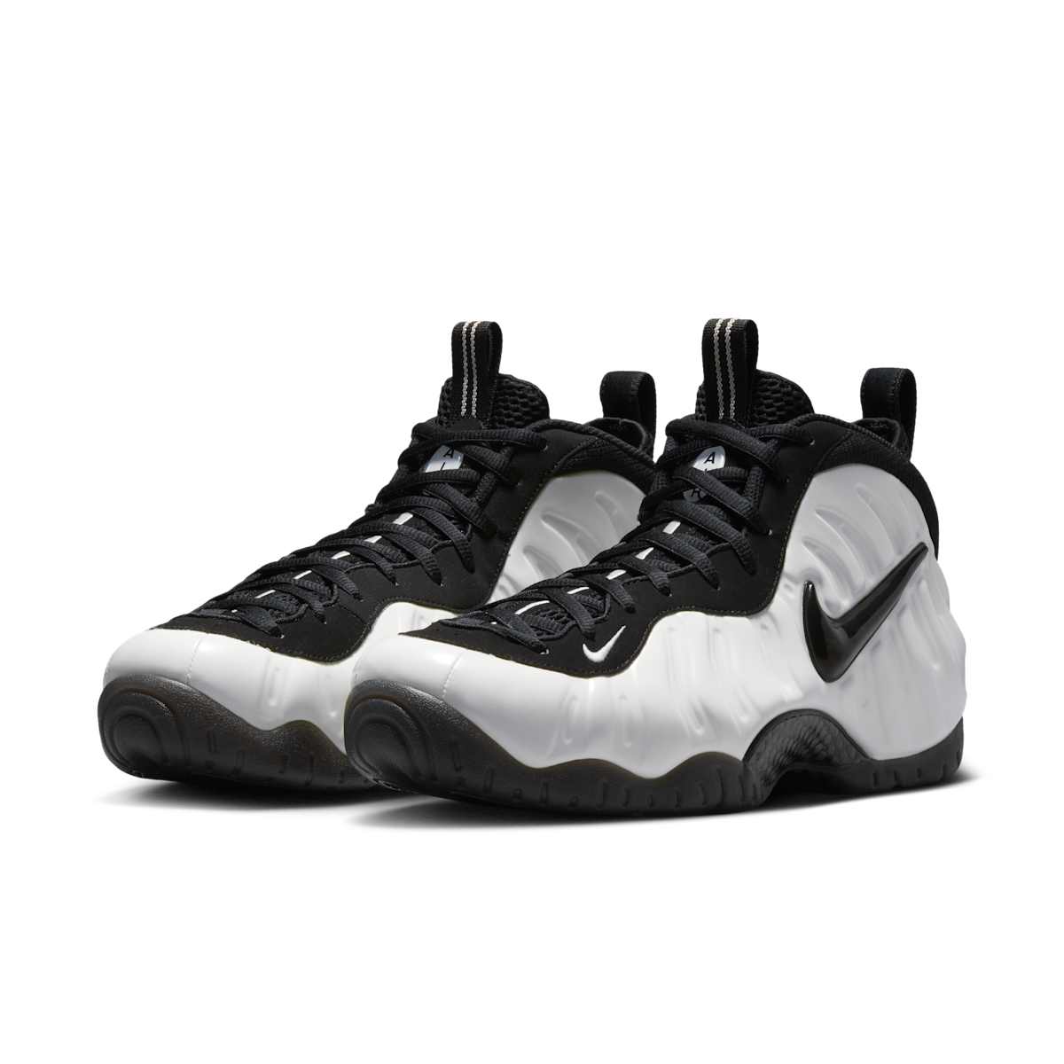 Par de Nike Air Foamposite Pro Premium Summit White en vista de tres cuartos, con carcasa blanca moldeada, Swoosh negro brillante, cordones negros y suela negra