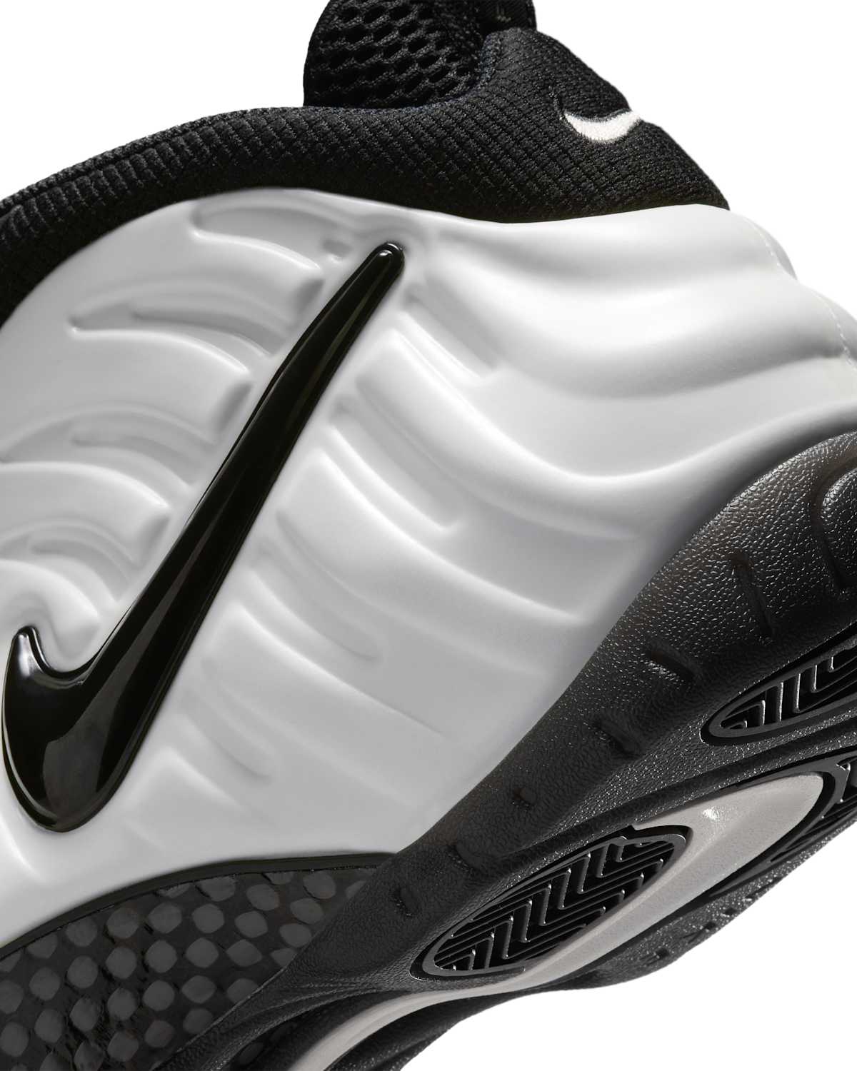 Primer plano del lateral de la Nike Air Foamposite Pro Premium Summit White con el Swoosh negro brillante sobre la carcasa blanca y la placa de fibra de carbono en el mediopié