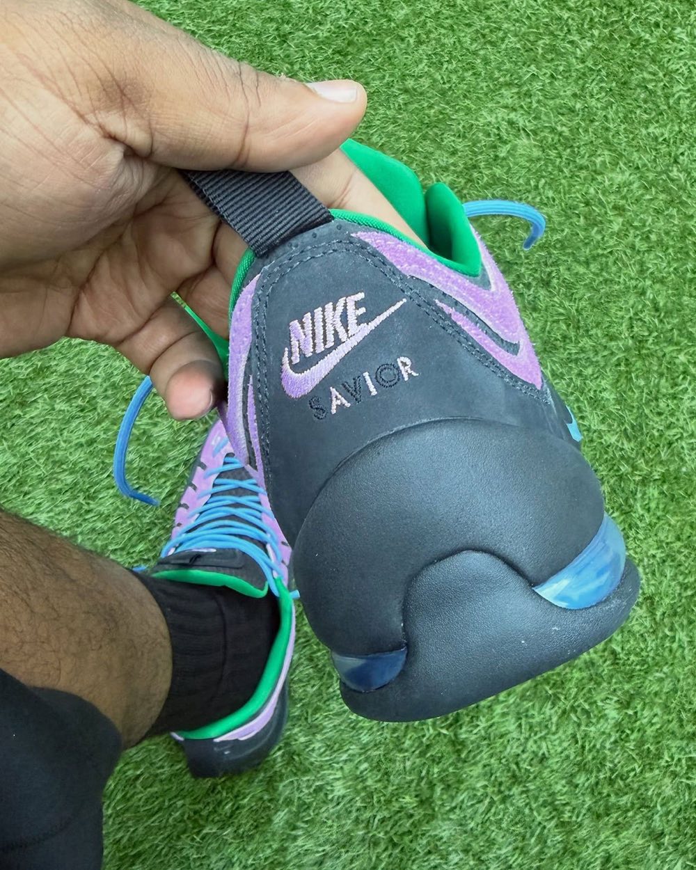 Talón del Jae Tips x Nike Air Bakin Low Purple Stardust en negro con el logo Nike y la palabra SAVIOR bordados en violeta y la cámara de aire a la vista
