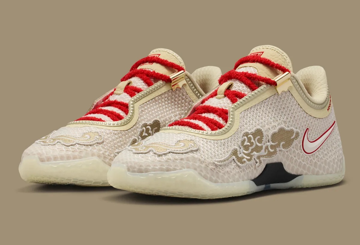 Par de Nike LeBron 24 Greater China en vista de tres cuartos sobre fondo caqui, con cordones rojos afelpados, nubes bordadas en dorado sobre la puntera y los laterales y suela translúcida