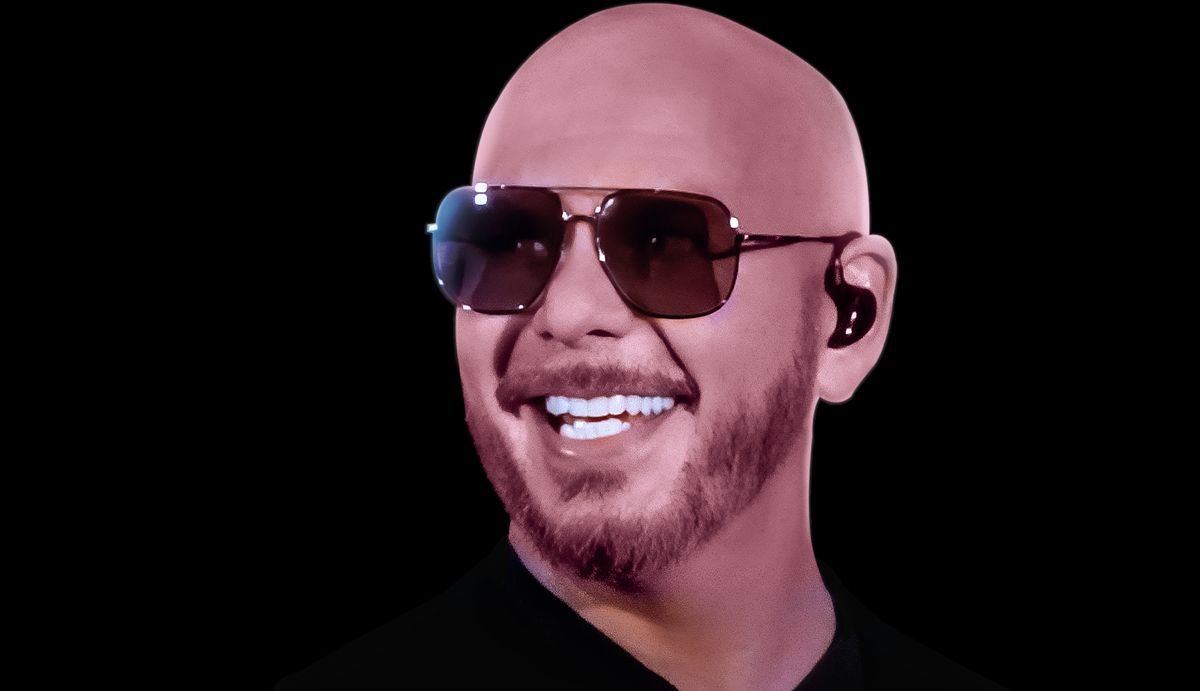 Foto de prensa oficial de Pitbull: el cantante sonríe con anteojos de sol aviador, barba candado y remera negra, sobre fondo negro