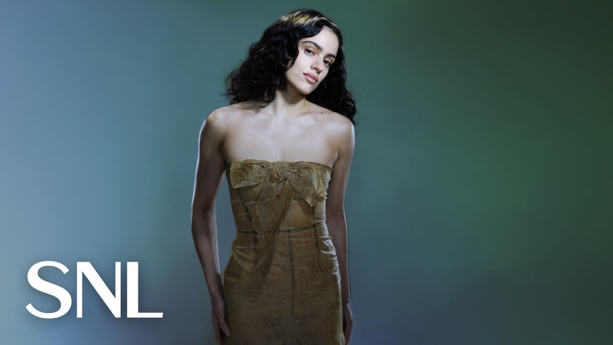 Retrato oficial de Rosalía para Saturday Night Live: la cantante posa con el pelo ondulado suelto y un vestido strapless dorado con un moño en el pecho, sobre un fondo verde azulado, con el logo de SNL abajo a la izquierda