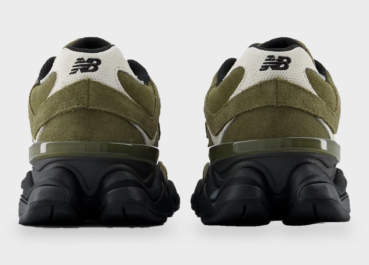 Vista trasera del par del New Balance 9060 Trail verde oliva sobre fondo gris claro, con el logo NB negro sobre un panel blanco en el talón, gamuza verde a los costados y la suela negra con su forma ondulada