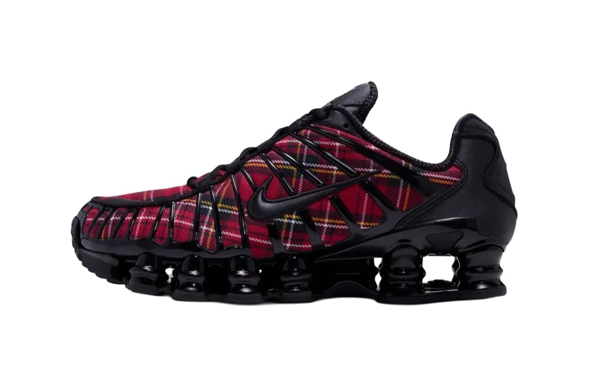 Nike Shox TL del Plaid Pack de perfil sobre fondo blanco, con tela escocesa roja debajo de la estructura negra y las columnas Shox negras