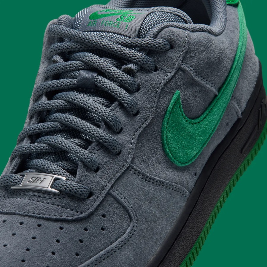 Detalle del lateral del Nike SB Air Force 1 Low de Nocturnal, con la gamuza gris, el Swoosh de gamuza verde, los cordones grises, la placa metálica SB-1 y la etiqueta Nike SB Air Force 1 verde en la lengüeta
