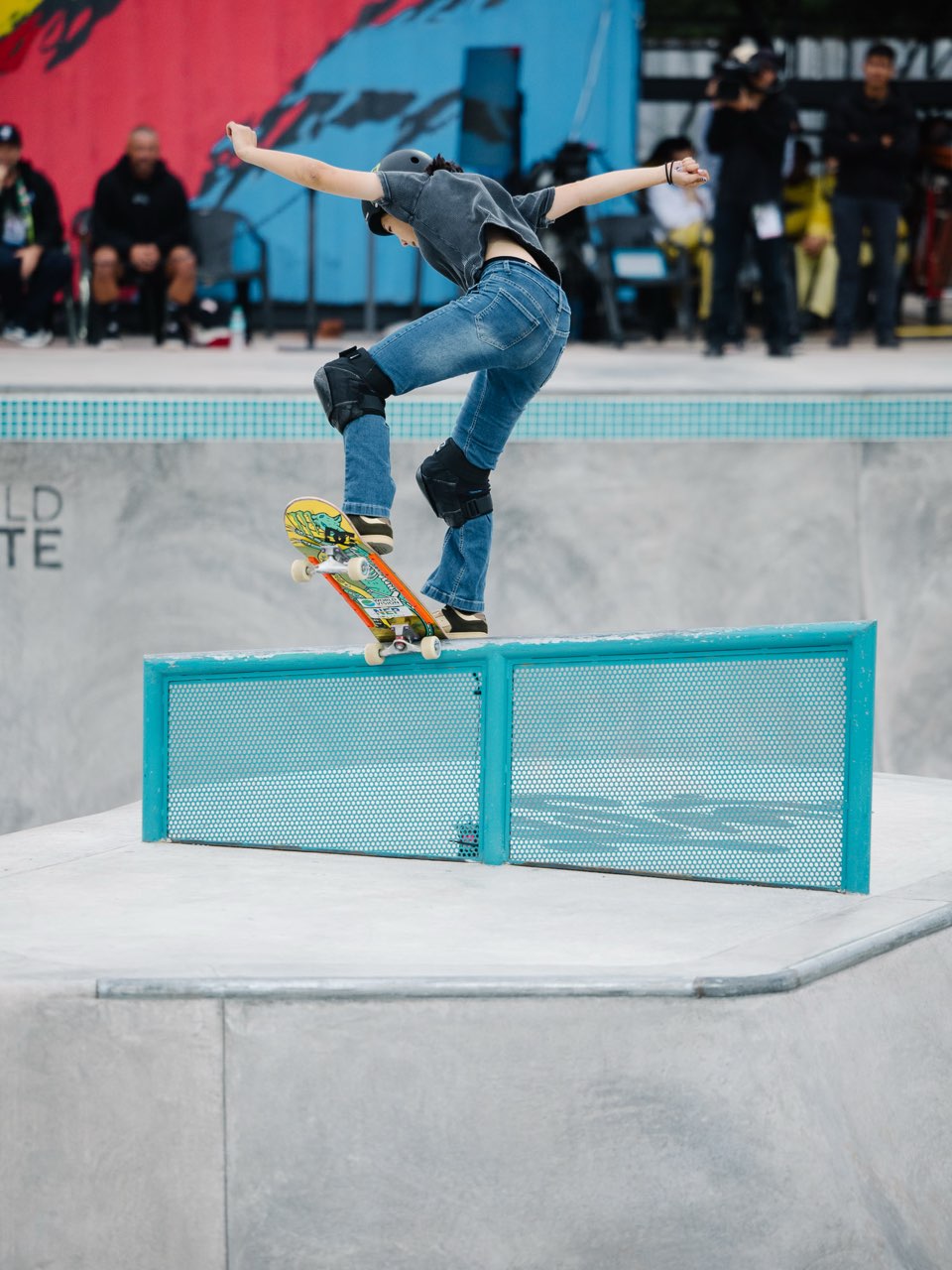 Mizuho Hasegawa, con casco negro y jeans, hace equilibrio con los brazos abiertos sobre una baranda celeste del park de Luque